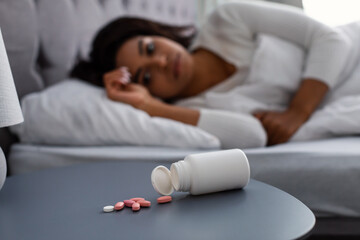 Obraz na płótnie Canvas Black woman suffering from insomnia, pills on table