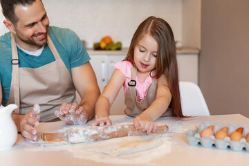 Obraz na płótnie Canvas Dad And Daughter Rolling Out Dough Baking Cookies Together Indoor