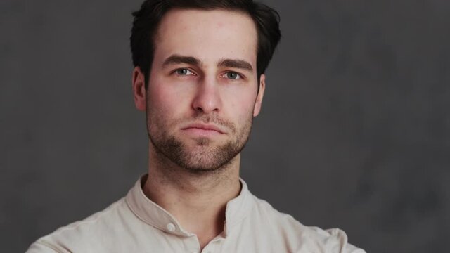 A Portrait Of A Man Straightening A Shirt Collar While Standing In A Studio