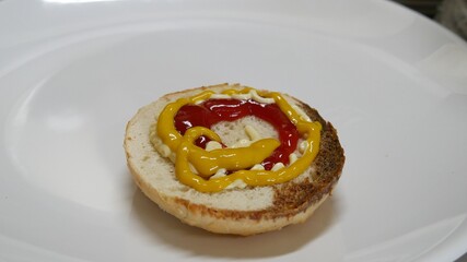 Half a slice of bun with catsup, mayonnaise and mustard.