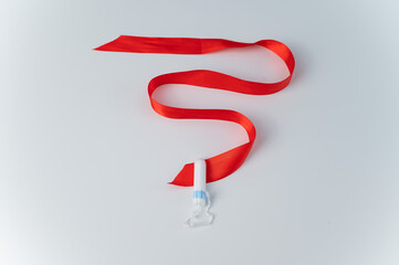 Tampon and red satin ribbon on a white background. Means of intimate hygiene of a woman during mentruation