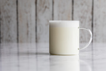 Warm frothy milk in a transparent glass cup