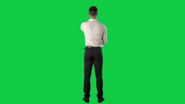 Back view of business man using interactive touch screen interface with various gestures. Full length on green screen chroma key background