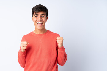 Handsome man over isolated blue background celebrating a victory in winner position