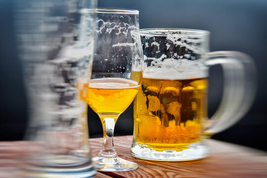mug and glasses empty and with drink on wooden surface, blurred image
