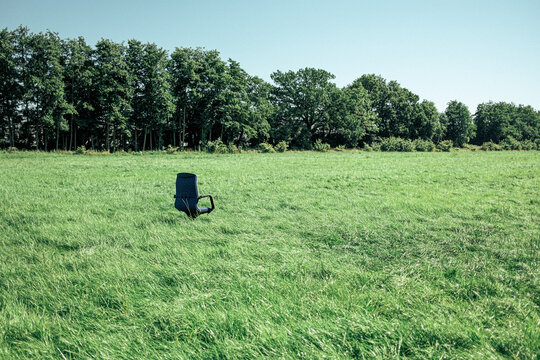 office chair standing in field in front of trees