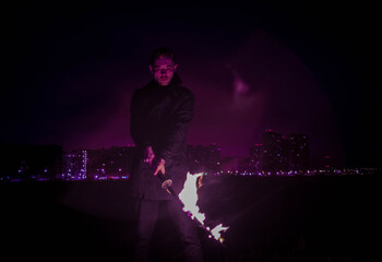 A man holding a hot sword, photo against the background of the city, in purple