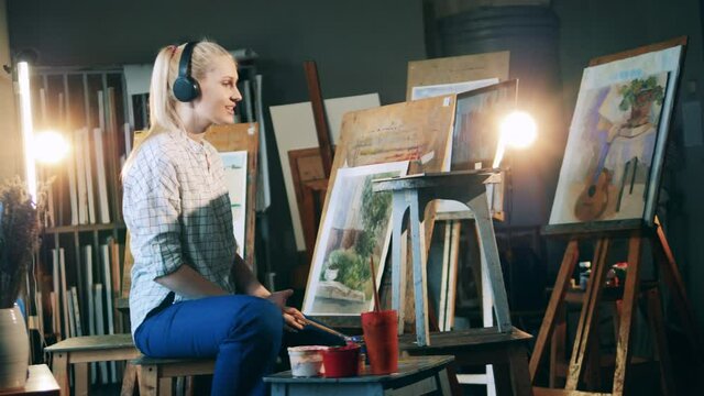 Blond lady is having an internet lesson and painting