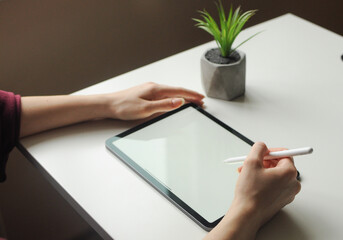 Person working on touch pad with stylus. Minimal interior. Remote freelance work