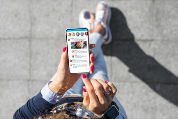 Woman using social media microblogging app on her phone - obrazy, fototapety, plakaty