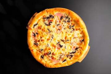 Pizza is not a wooden board. Black background. close-up.