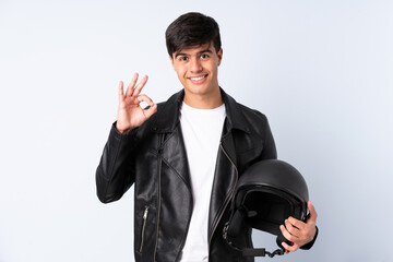 Man with a motorcycle helmet over isolated blue background showing an ok sign with fingers