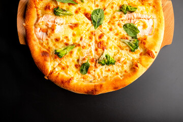 Pizza is not a wooden board. Black background. close-up.