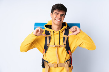 Young mountaineer man with a big backpack over isolated blue background proud and self-satisfied