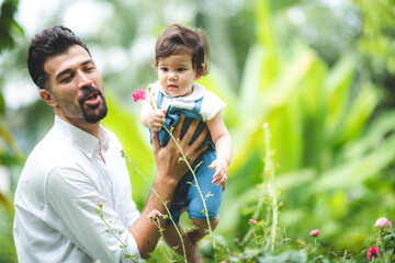 Fototapeta premium family person concept, father and baby child joy playing in the outdoor nature grass flower garden, having fun and happy smiling, childhood and parent love together in summer at home