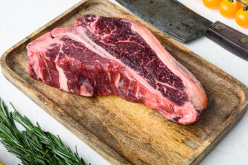 Raw fresh meat t-bone steak with spices, garlic and rosemary, on white stone  background
