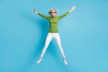 Fototapeta na wymiar Full size photo of happy excited cheerful smiling girl in glasses jumping in star pose isolated on blue color background