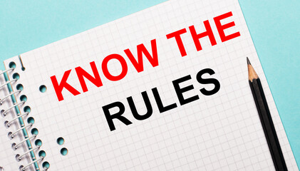 Fototapeta premium On a light blue background, a checkered notebook with the words KNOW THE RULES and a black pencil.