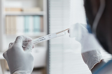 Close-up of doctor in protective gloves holding test tube for analysis of covid