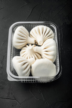Manti or manty dumplings, popular asian dish, in plastic tray, on black stone background