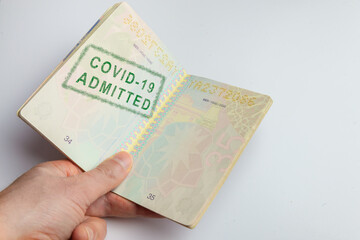 Concept representing a hand holding a vaccination passport with a stamp indicating that the passenger has been admitted: he is compliant with the vaccination requirements