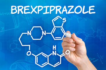 Hand with pen drawing the chemical formula of Brexpiprazole