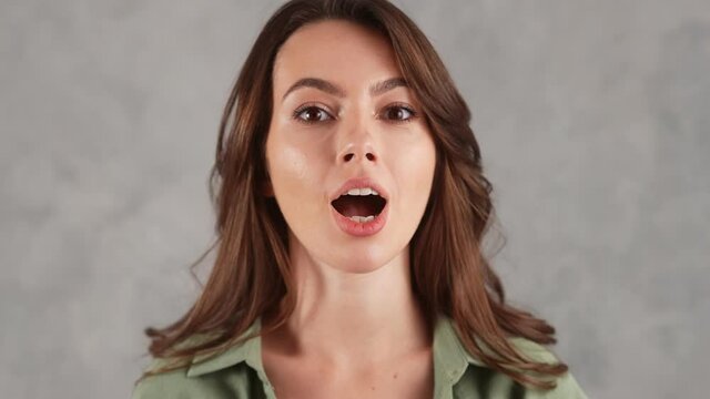 A close-up shot of a smiling woman showing grimace in the gray studio
