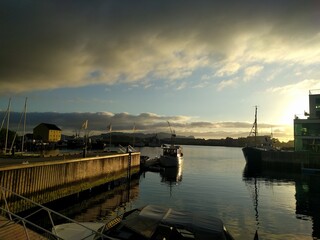 sunset over the harbor with mirror water and some boats