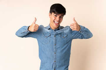 Fototapeta premium Handsome man over isolated beige background giving a thumbs up gesture