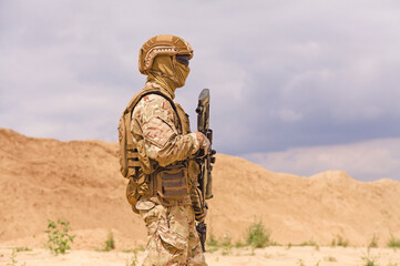 Equipped and armed soldier in camouflage with rifle in the desert. Concept of military anti-terrorism operations, special operations of NATO forces.