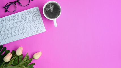 Stylish workspace coffee cup, flowers, notebook and keyboard on purple background.