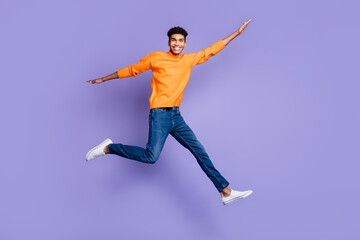 Fototapeta na wymiar Full body photo of handsome dark skin man wear jeans jump go empty space hands wings isolated on purple color background