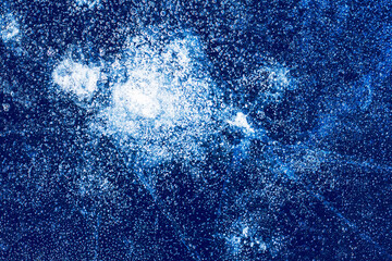 Ice texture with frozen bubbles and cracks on a dark blue background. Beautiful abstract decorative background. Stylish abstract design for wraps, gift, fabric, textile, furnishing. Winter pattern.