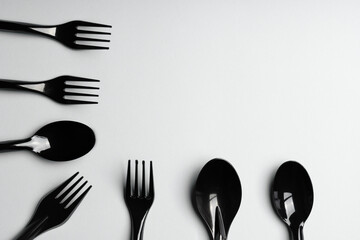 Forks and spoons on gray background. Plastic cutlery, ecology, environmental pollution by plastic, disposable tableware, waste recycling concept. copyspace, flat lay