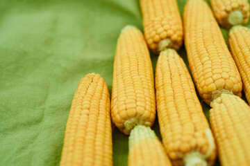 close-up ears of corn lie on a green linen tablecloth