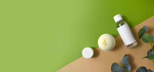 Mock up spa cosmetic flat lay with bath bomb, lotion bottle and eucalyptus  leaves on green and beige background. Eco beauty products, wellness, skin or body care. Minimal concept, top view. Banner.