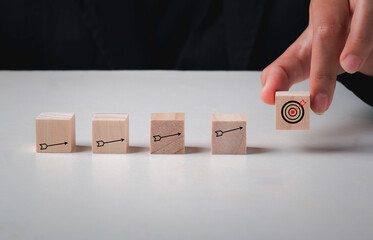 Hand arranging wood cube with arrow icon action plan, goal and target, success and business target concept, project management, company strategy development.