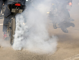 high power motorcycle with racer. Smoke from under the wheels, the racer in the smoke. rear view of an athlete driving a motorcycle. burnt rubber scatters from under the wheels.