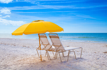 Siesta Key Beach yellow umbrella and beach chairs with blue sky and ocean.