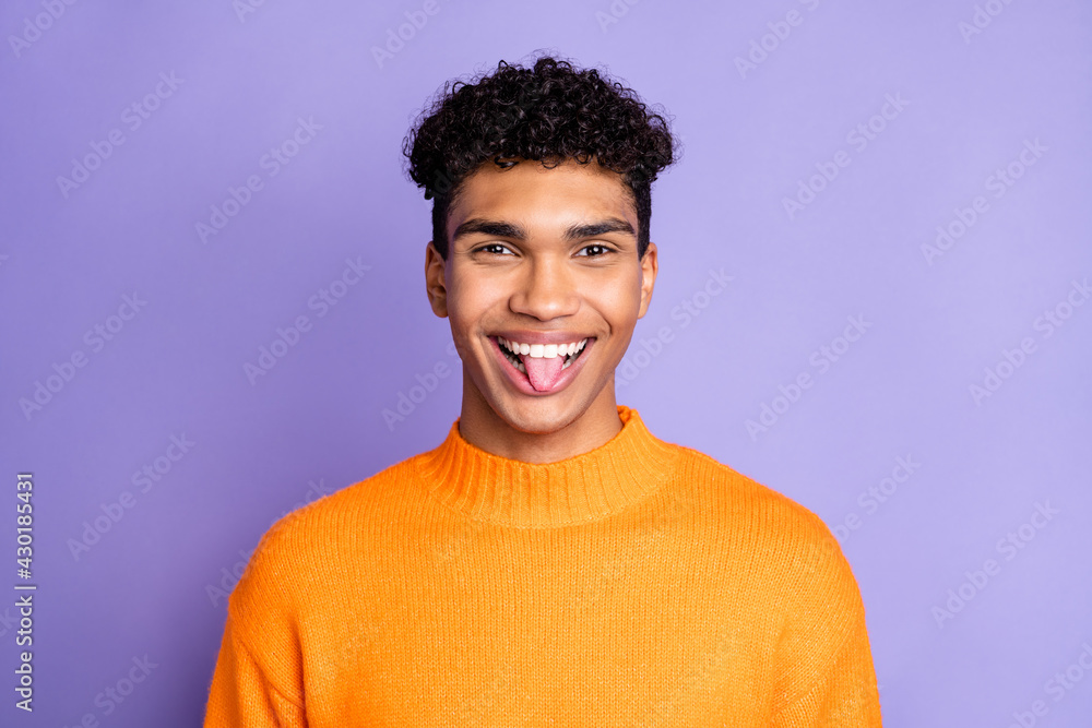 Sticker Photo of childish funny dark skin man wear orange sweater showing tongue isolated violet color background