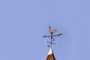 Obraz premium vintage rooster weathervane, cardinal points north, south, east and west, with blue sky in the background