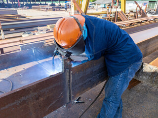 The welder is welding add joint of steel H-beam with process Flux Cored Arc Welding(FCAW) and...
