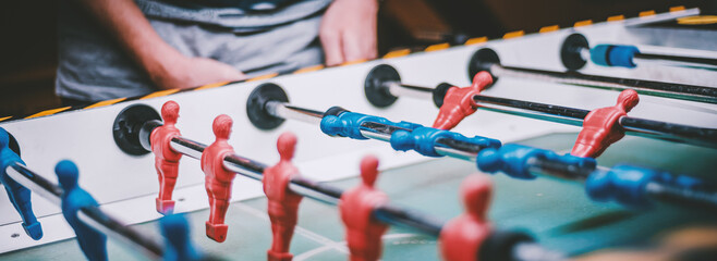 man plays table football. Detail of man's hands playing the kicker