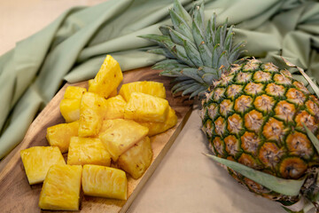 Fresh sliced pineapple on wooden tray on table.