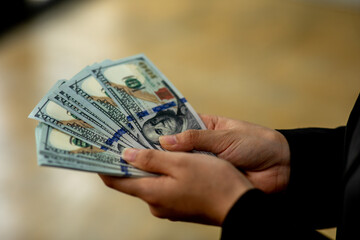 A Business woman Hands counting us dollar bills,Concept of business ,savings, salary, payment and funds. woman counts cash bills.