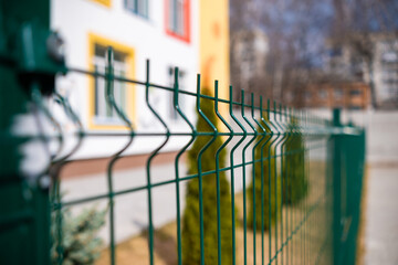 Green fence on a bright day near the school