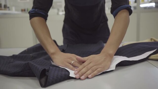 stylist male hands compare sleeve paper pattern with blue shirt, slow motion