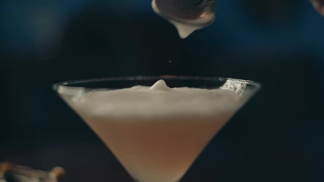 Close up of classy alcoholic cocktail in glass and spoon aligning foam selective focus, slow motion