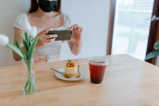 A blogger's hand uses a smartphone to take pictures of food in cafe.