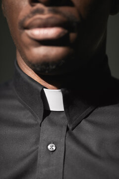 Close-up Of African Priest In Collar Isolated In Black Background